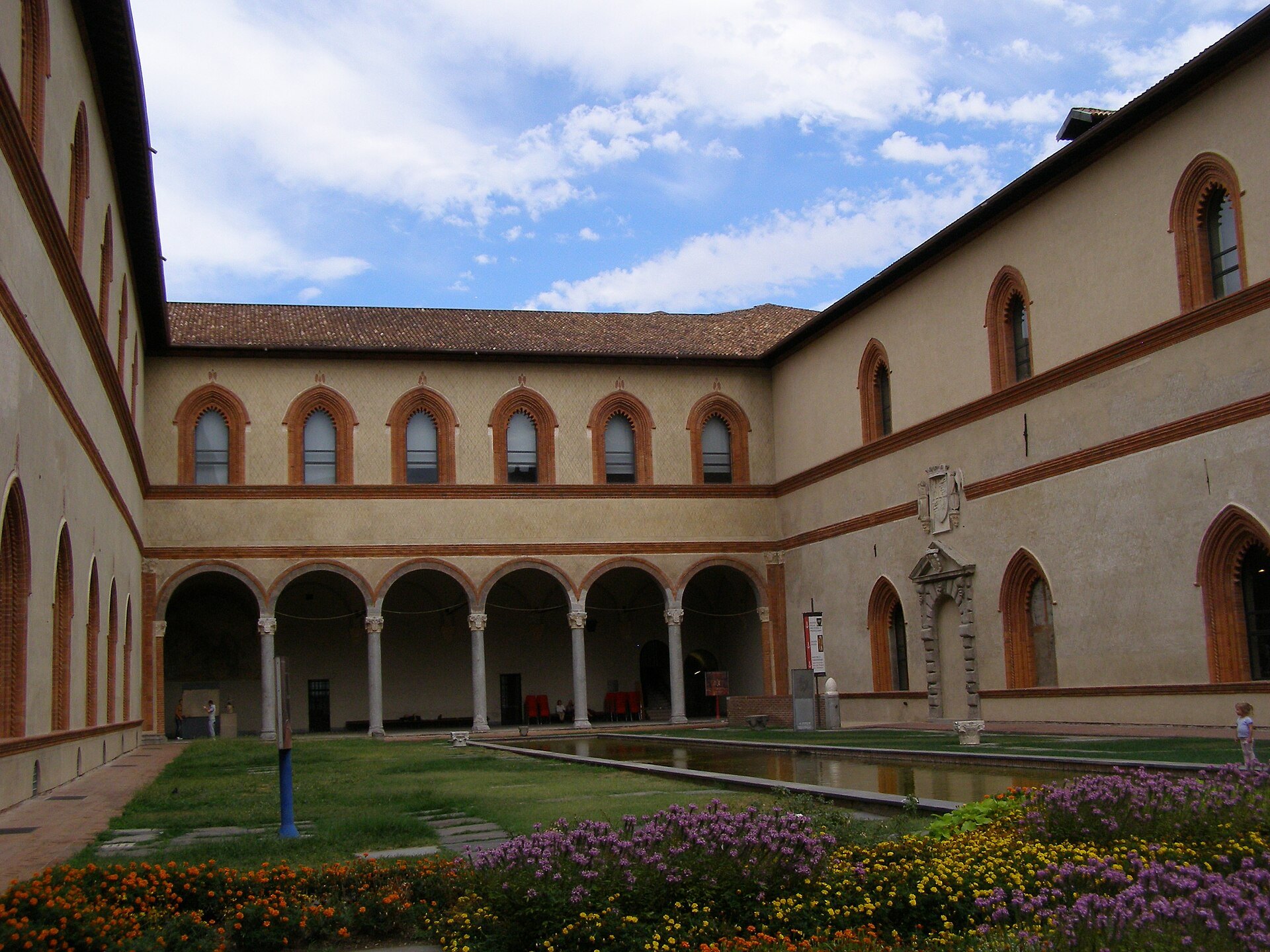The Cortile Ducale inside the castle, brick arcades around a planted courtyard