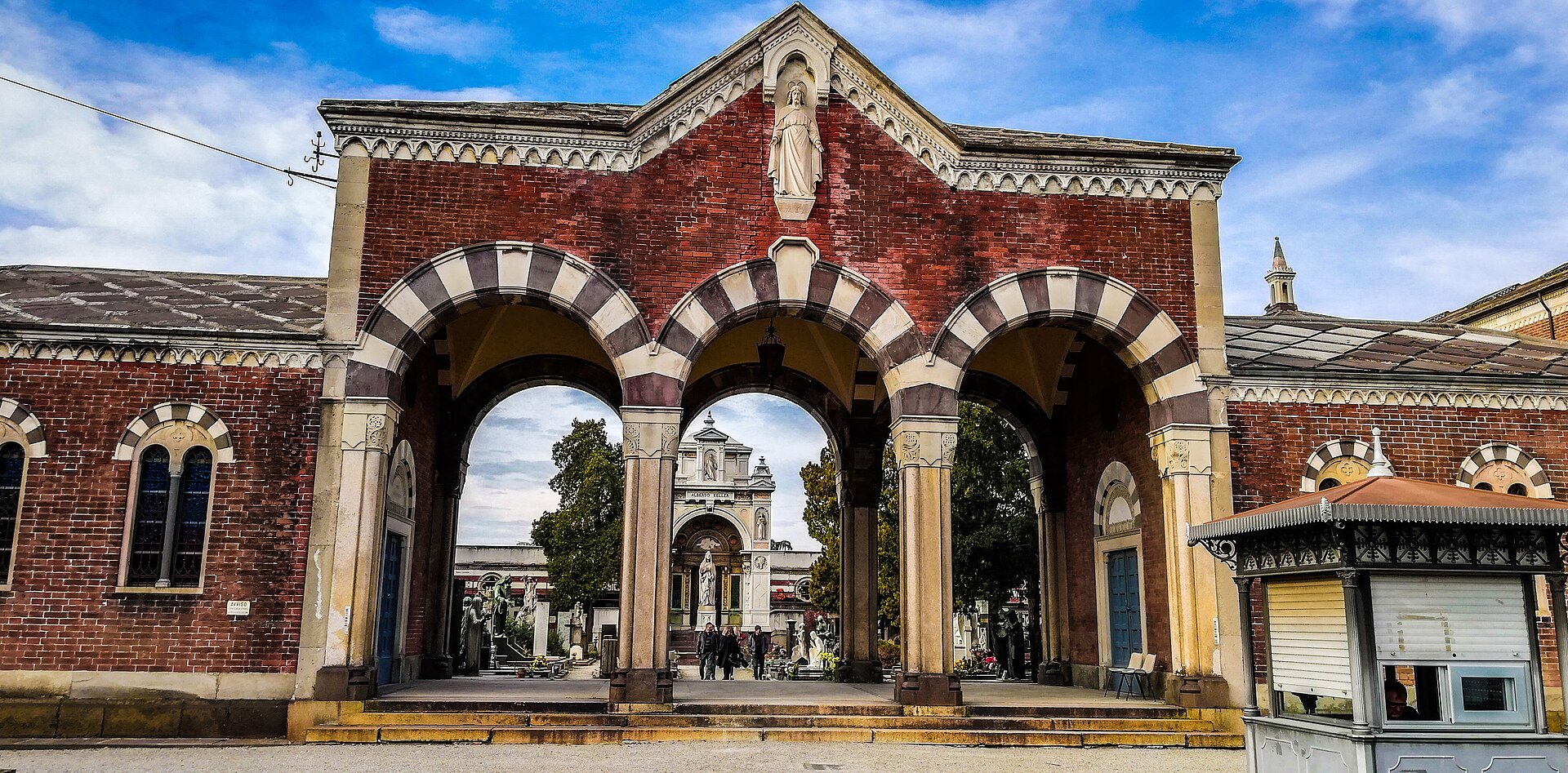 The Famedio at the Monumental Cemetery, its brick and stone front behind the entrance gates