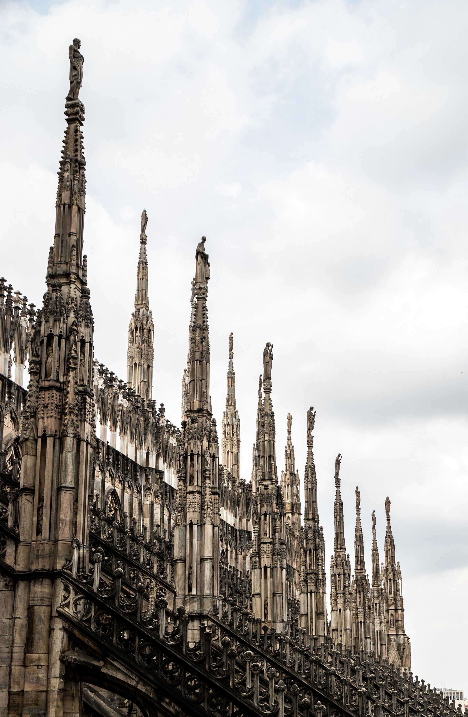 A row of spires along the cathedral roof against a pale sky