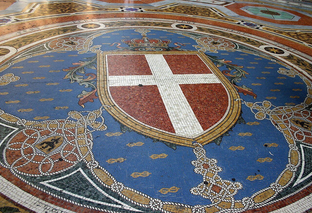 The mosaic coat of arms set into the Galleria floor, a white cross on blue