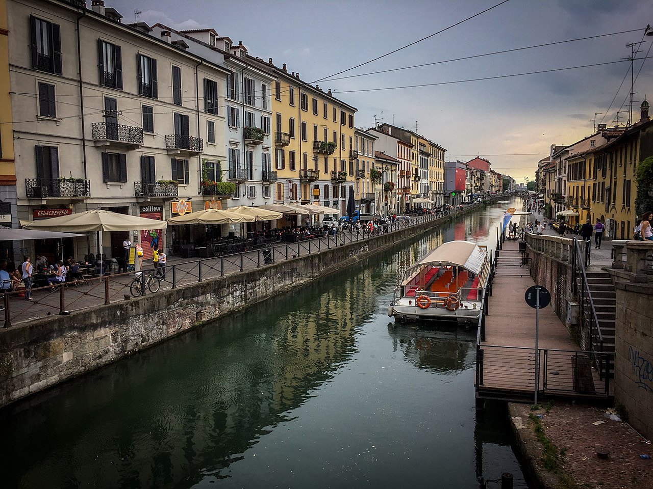 Tables and umbrellas along the Naviglio towpath in the afternoon