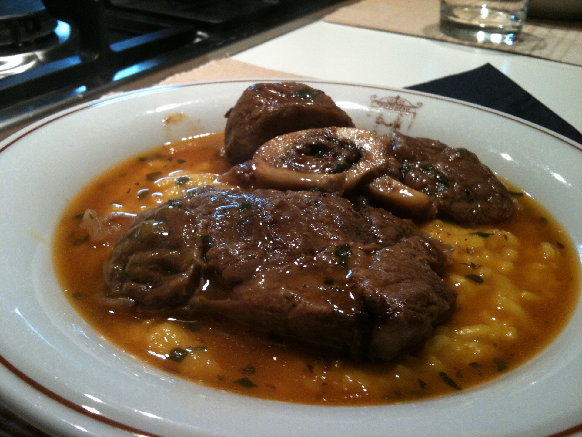 Ossobuco served with saffron risotto alla milanese on a white plate
