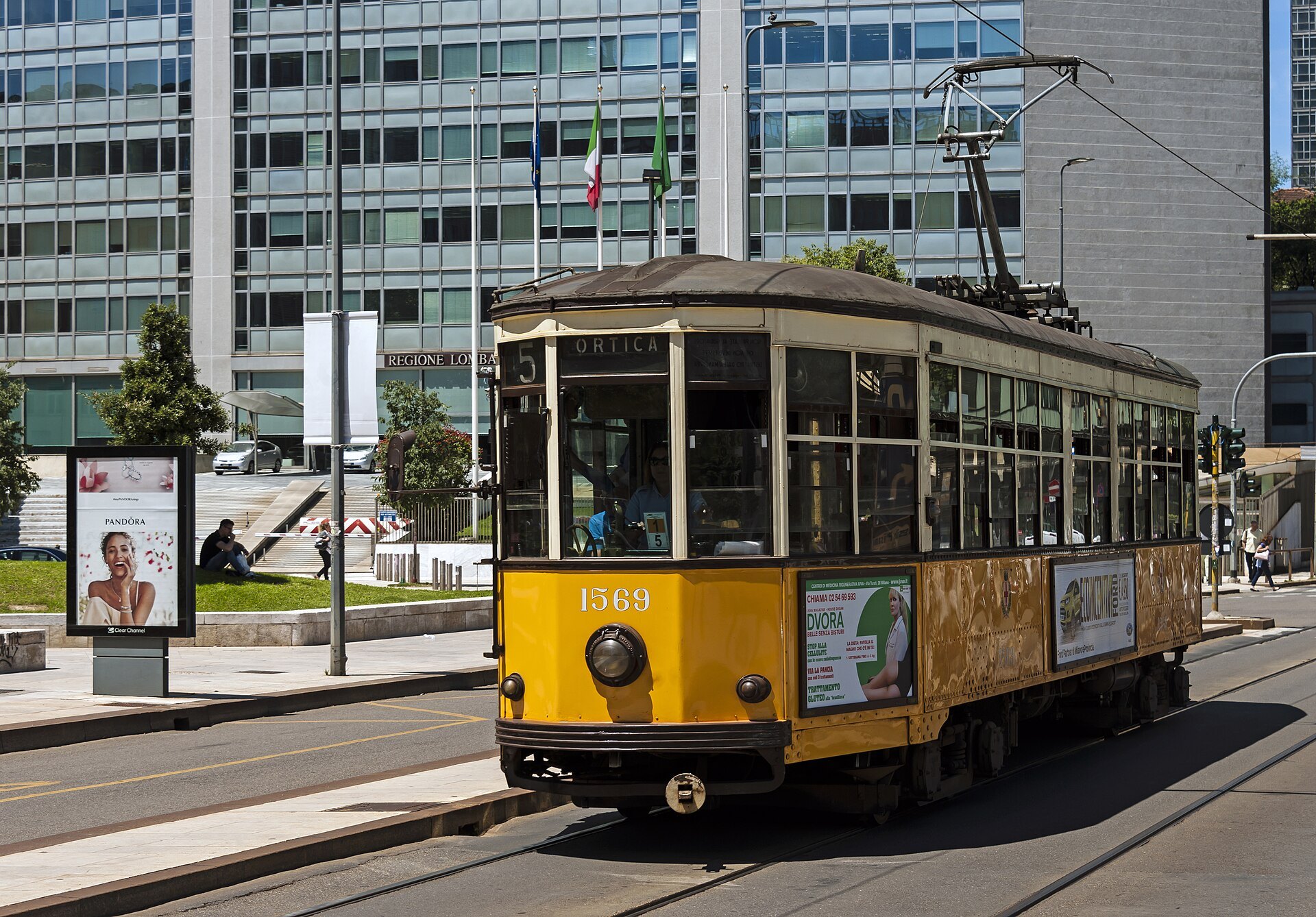 An orange 1928 Carrelli tram running along a Milan street