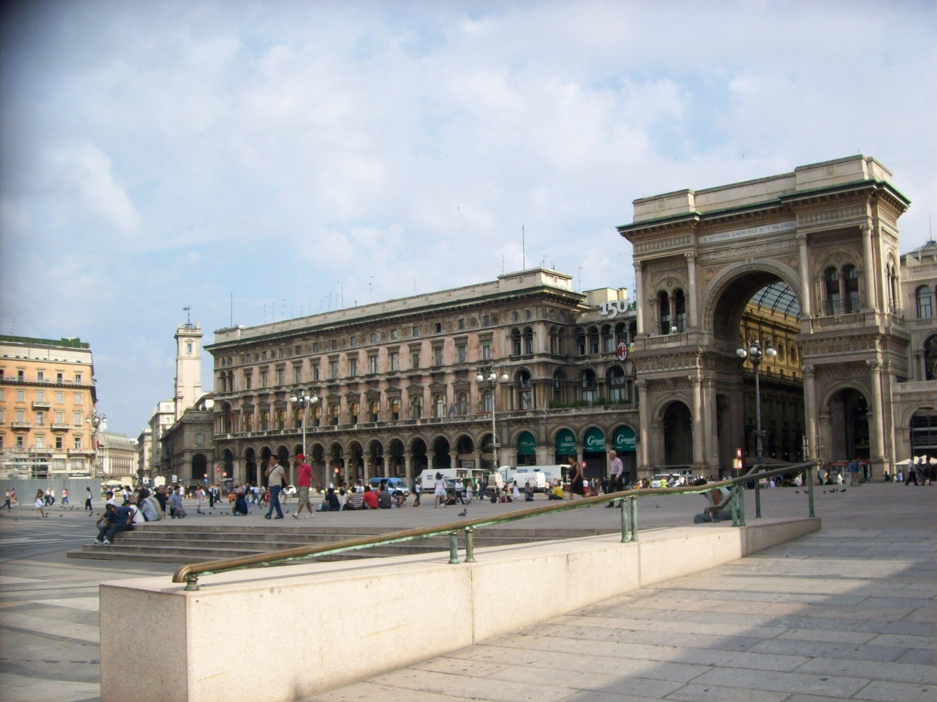 Piazza del Duomo with the arched entrance to the Galleria and people crossing the square